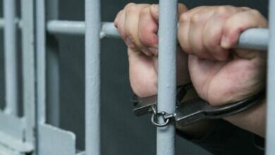 Человек в наручниках за решеткой